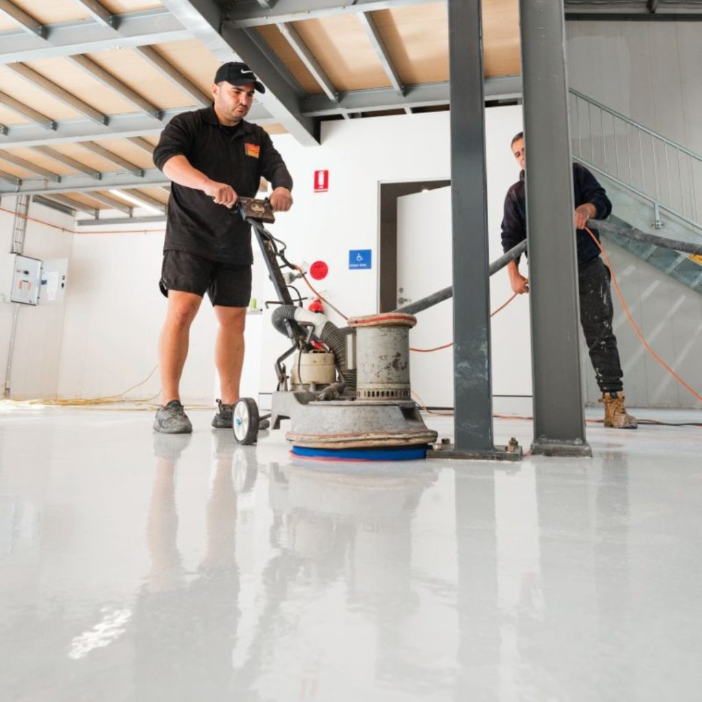 Two men operating a machine to clean a floor, showcasing Grind and Seal Floor Services in Sydney.