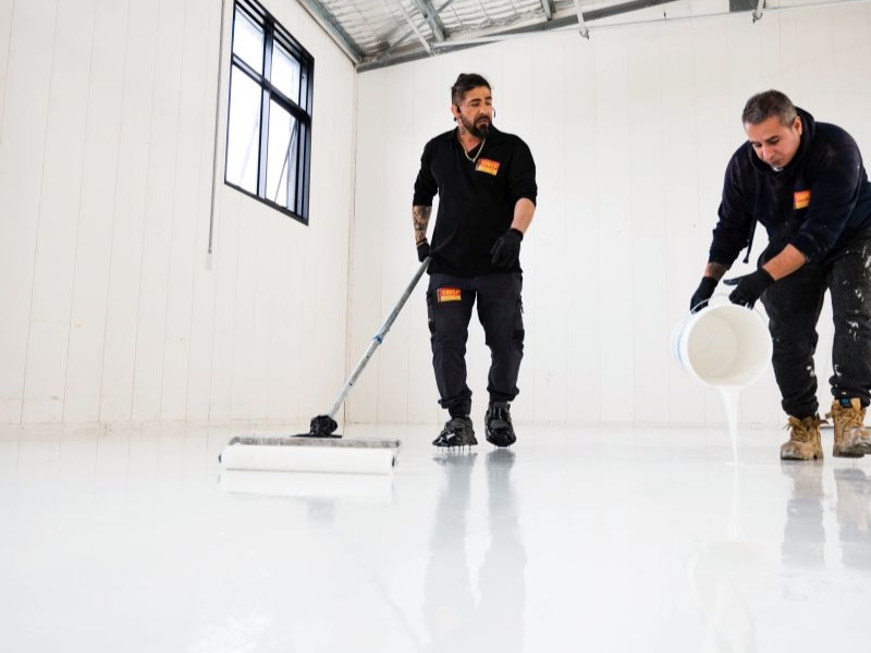 Epoxy flooring application in progress in a warehouse, highlighting the durability and strength of the epoxy surface.