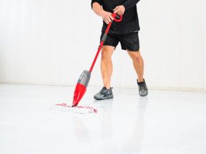 Worker cleaning epoxy flooring in a warehouse, showcasing the durability and easy maintenance of the surface.