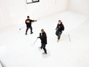 Three workers applying different epoxy coating types in a large room for a smooth and durable finish.