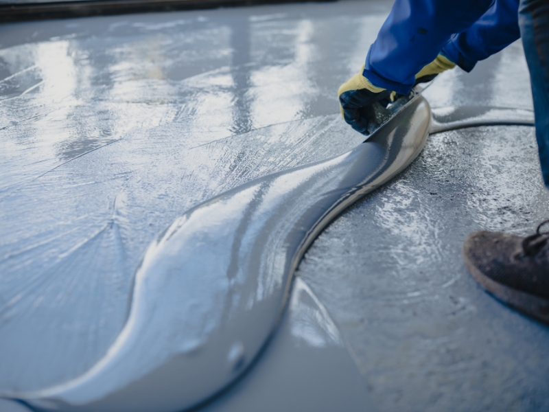 Epoxy resin floor being smoothed out in a workshop, showcasing its durability and smooth finish for heavy use.