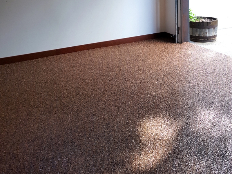 Close-up of epoxy floor cracking in garage near open entrance, illustrating common wear and tear.