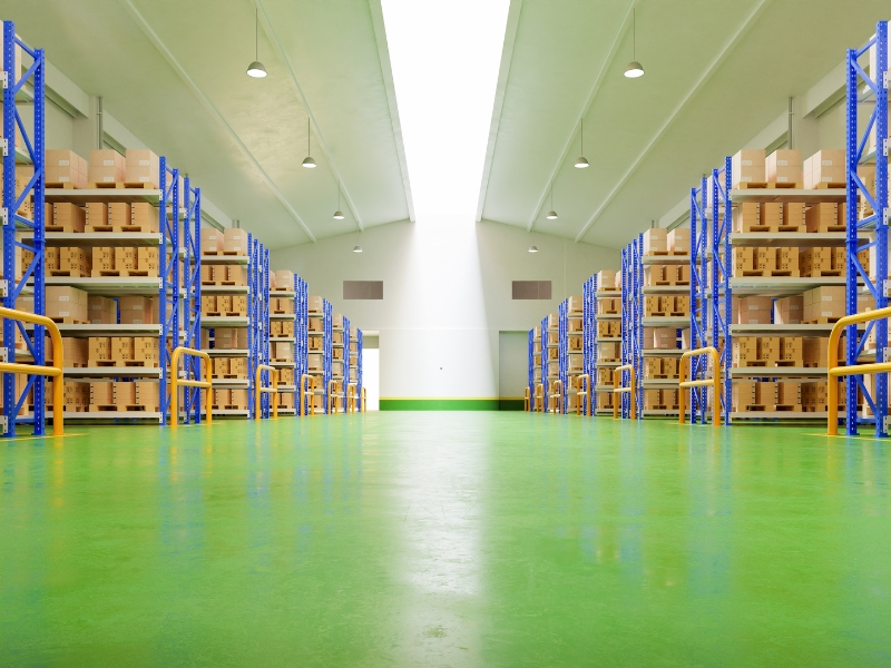 Spacious floor storage warehouse with green epoxy flooring and organized shelves filled with boxes. Durable and efficient setup.