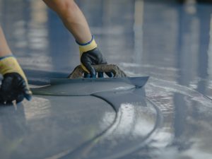 A worker maintaining a smooth, shiny epoxy floor in a warehouse.