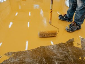 Applying a coat of best epoxy floor paint with a roller for a durable and long-lasting finish.