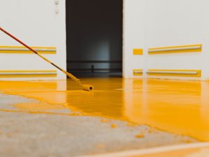 A man applying a type of epoxy flooring to a garage floor.